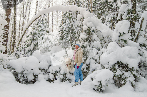 Image of A woman with a dog in a snow-covered winter forest