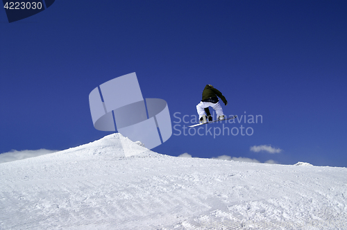 Image of Snowboarder jump in terrain park at ski resort on sun winter day
