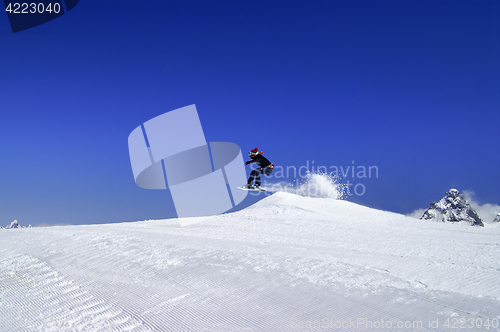 Image of Snowboarder jumping in snow park at ski resort on sun winter day