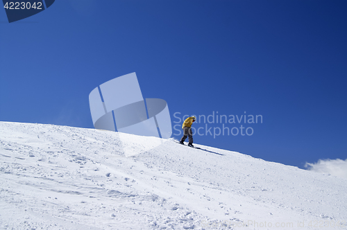 Image of Snowboarder downhill on off-piste slope and blue clear sky