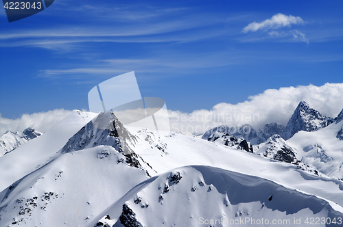 Image of Winter mountains with snow cornice and blue sky with clouds in n