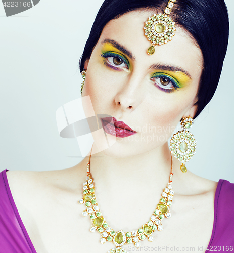 Image of young pretty caucasian woman like indian in ethnic jewelry close up on white, bridal bright makeup fashion