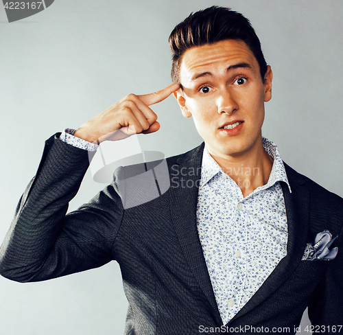 Image of young pretty business man standing on grey background, modern hairstyle, gesturing emotional
