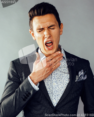 Image of young pretty business man standing on grey background, modern hairstyle, gesturing emotional