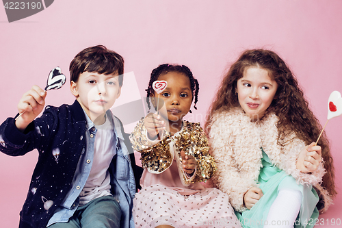 Image of lifestyle people concept: diverse nation children playing together, caucasian boy with african little girl holding candy happy smiling 