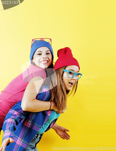 Image of lifestyle people concept: two pretty young school teenage girls having fun happy smiling on yellow background 