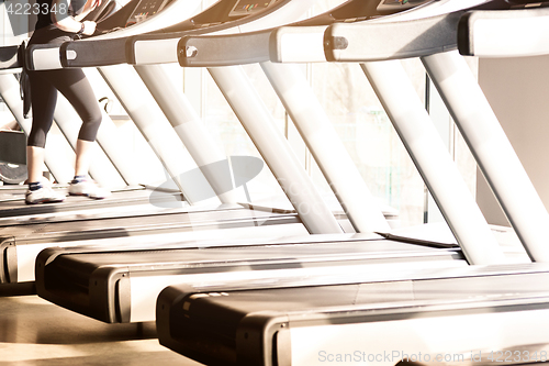 Image of Woman running in a gym on a treadmill concept for exercising, fitness and healthy lifestyle