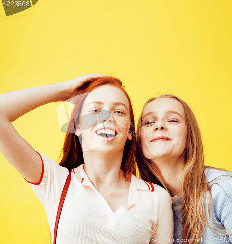 Image of lifestyle people concept: two pretty young school teenage girls having fun happy smiling on yellow background 