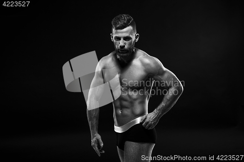 Image of The torso of attractive male body builder on black background.