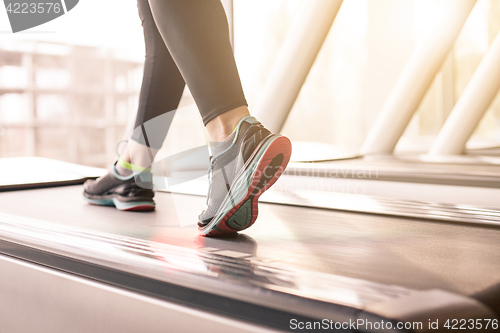 Image of Woman running in a gym on a treadmill concept for exercising, fitness and healthy lifestyle