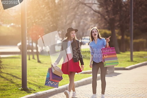 Image of Two girls walking with shopping on city streets