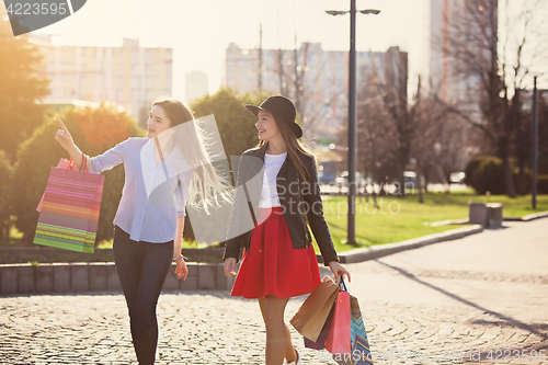 Image of Two girls walking with shopping on city streets