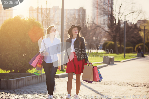 Image of Two girls walking with shopping on city streets