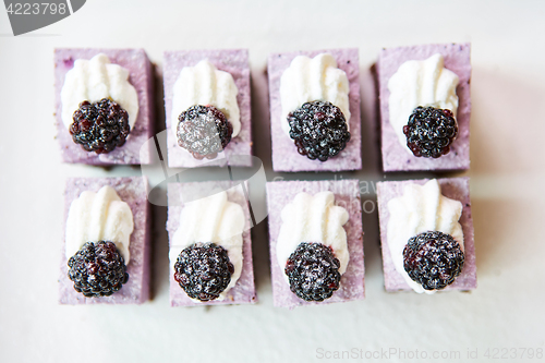 Image of The rows of sweet and tasty cakes with blackberries.