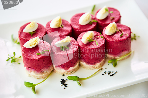Image of layered salad with herring, beets, carrots, onions, potatoes and eggs close-up on a plate. horizontal.