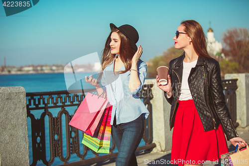 Image of Two girls walking with shopping on city streets