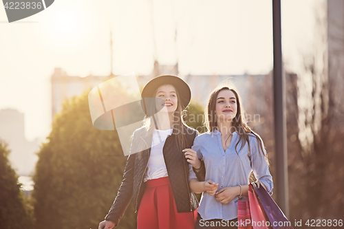 Image of Two girls walking with shopping on city streets