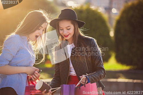 Image of Two girls walking with shopping on city streets