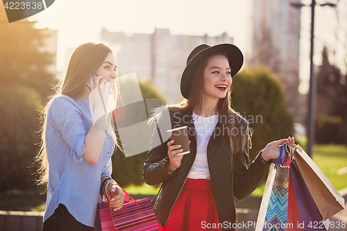 Image of Two girls walking with shopping on city streets