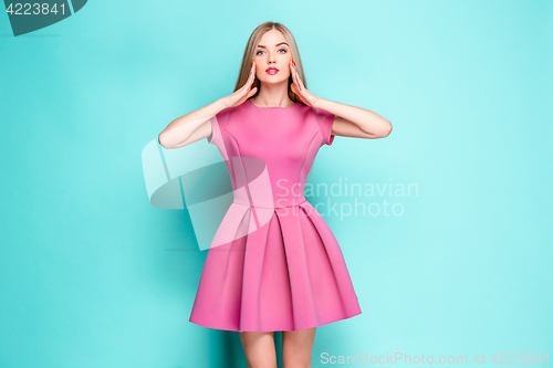 Image of Smiling beautiful young woman in pink mini dress posing at studio