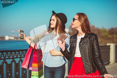 Image of Two girls walking with shopping on city streets