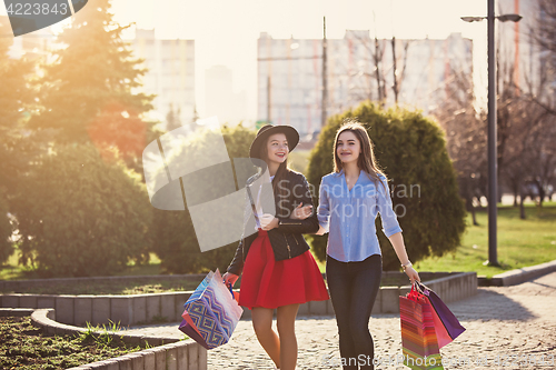 Image of Two girls walking with shopping on city streets