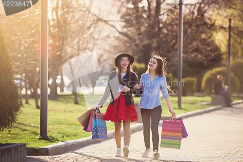 Image of Two girls walking with shopping on city streets