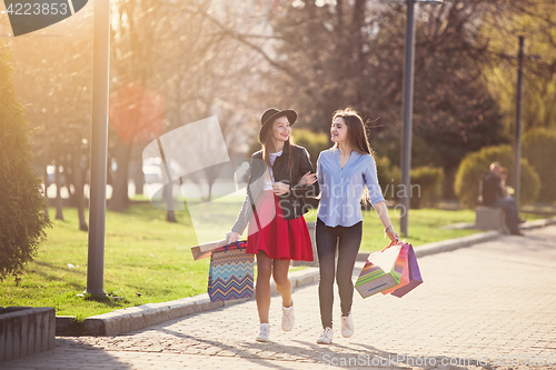 Image of Two girls walking with shopping on city streets