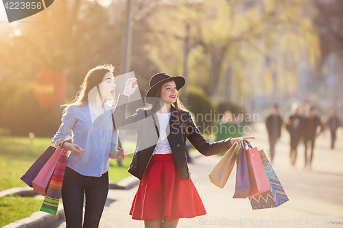 Image of Two girls walking with shopping on city streets