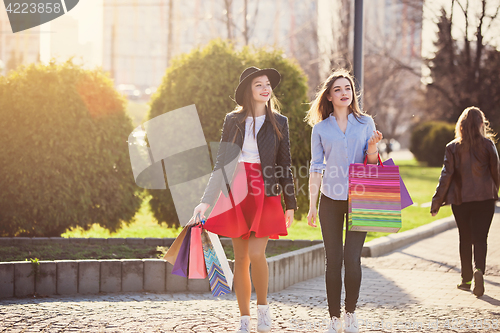 Image of Two girls walking with shopping on city streets