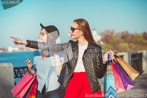 Image of Two girls walking with shopping on city streets