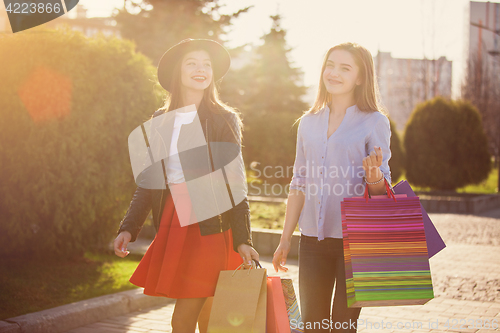 Image of Two girls walking with shopping on city streets