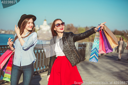 Image of Two girls walking with shopping on city streets