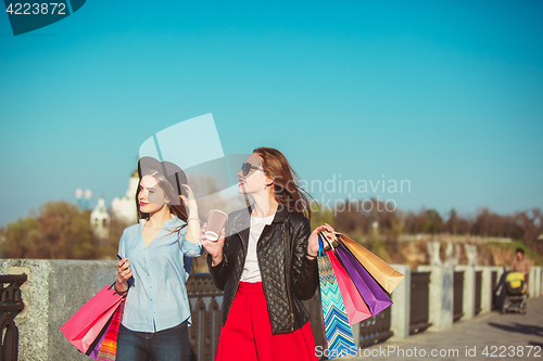 Image of Two girls walking with shopping on city streets