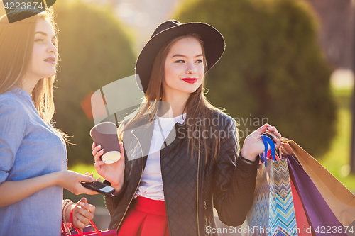 Image of Two girls walking with shopping on city streets
