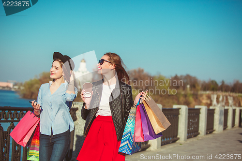 Image of Two girls walking with shopping on city streets