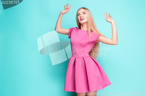 Image of Smiling beautiful young woman in pink mini dress posing at studio