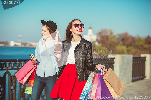 Image of Two girls walking with shopping on city streets