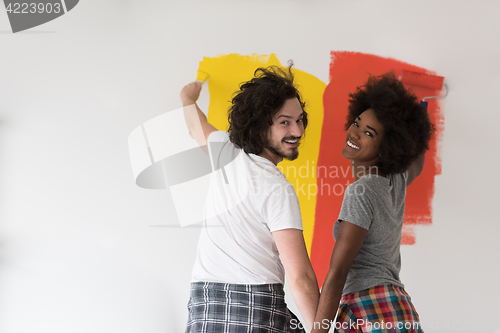 Image of multiethnic couple painting interior wall