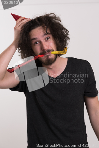 Image of Portrait of a man in party hat blowing in whistle