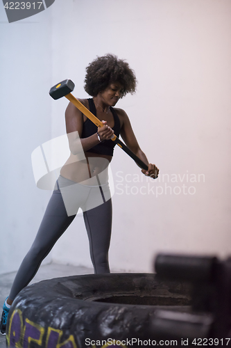 Image of black woman workout with hammer and tractor tire