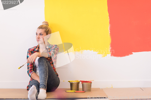 Image of young female painter sitting on floor