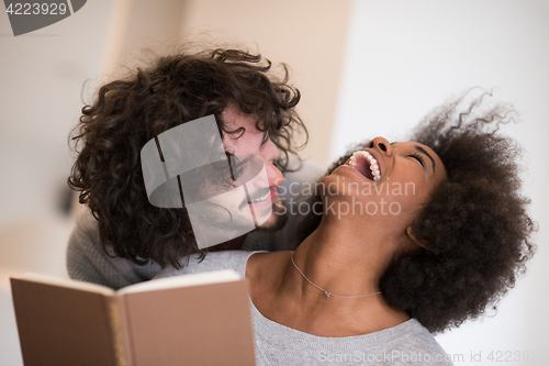 Image of multiethnic couple hugging in front of fireplace