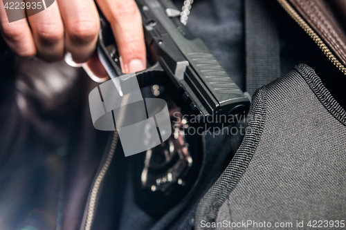 Image of Closeup of police officer taking out handgun from holster at nig