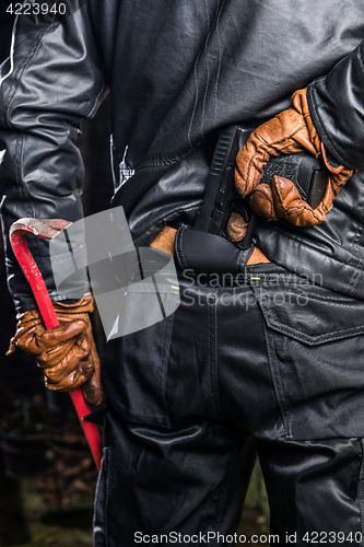 Image of Midsection rear view of burglary holding crowbar and gun at nigh