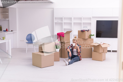 Image of woman with many cardboard boxes sitting on floor