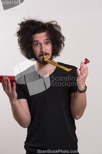 Image of Portrait of a man in party hat blowing in whistle