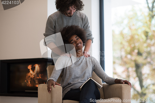 Image of multiethnic couple hugging in front of fireplace