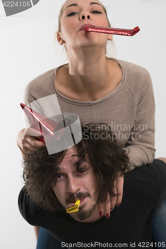 Image of couple in party hats blowing in whistle