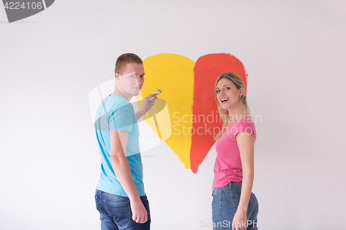 Image of couple are painting a heart on the wall